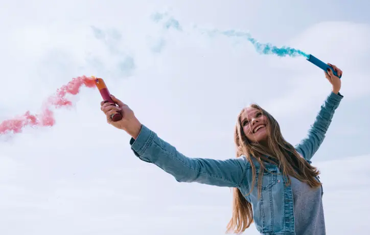 woman holding colored smoke bombs